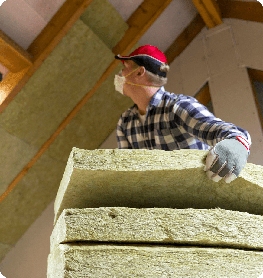 Worker wearing mask and gloves holding mineral wool insulation batts.