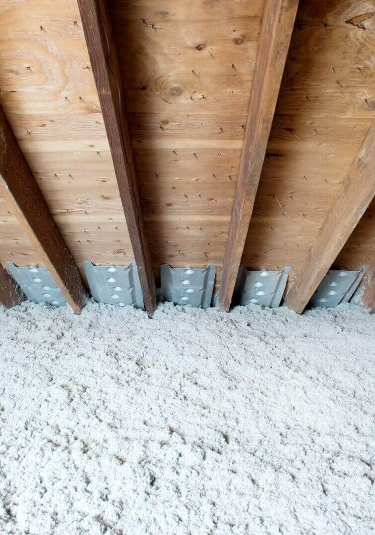 Wooden attic ceiling with loose-fill insulation.