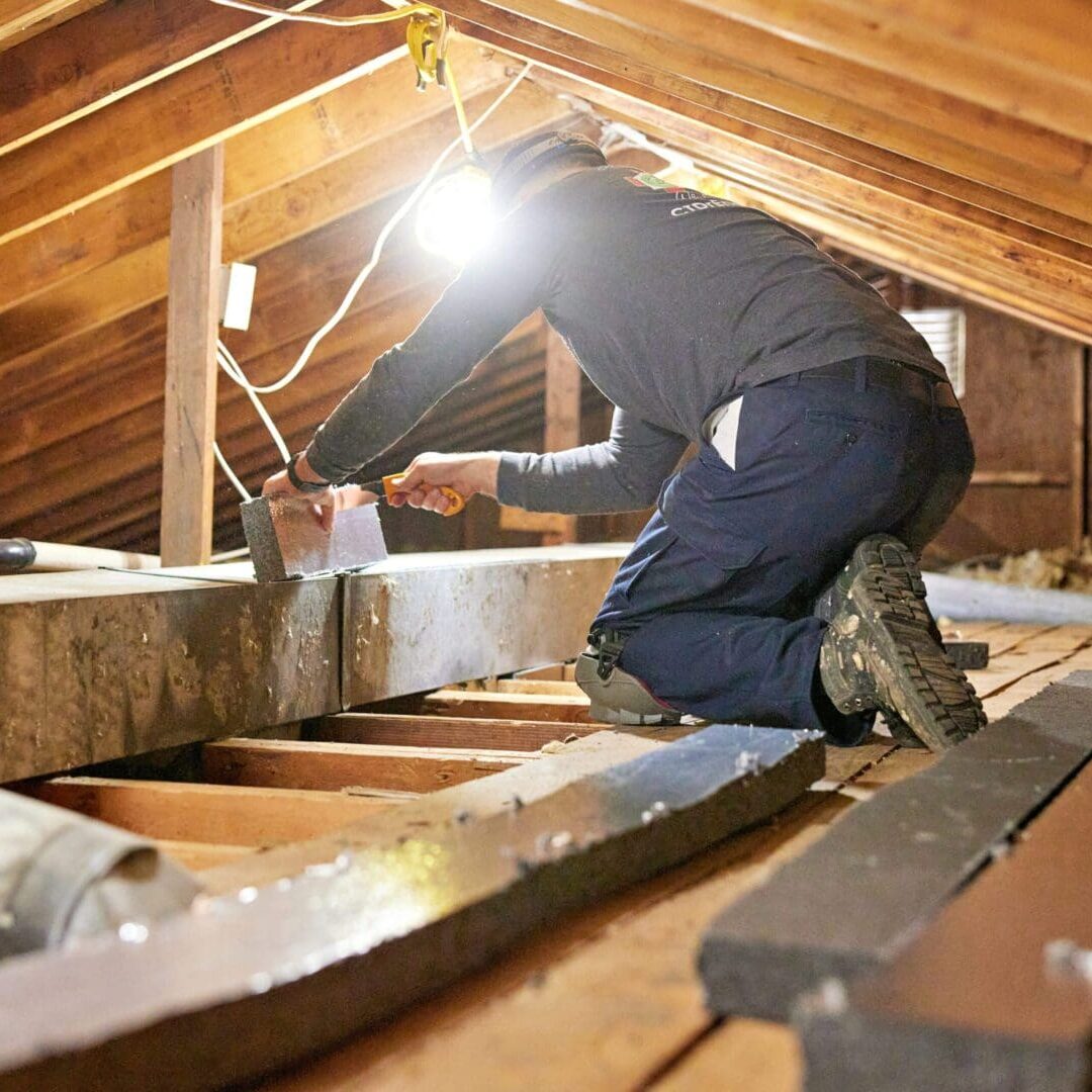 Professional examining damp floor before crawl space waterproofing in Tualatin, OR.